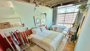A bedroom with a bed, a vanity, a window, and a plant. - 2002B (São Paulo)