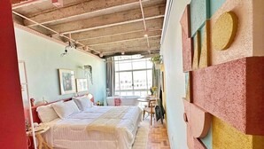 A bedroom with a bed, a window, and a wall with geometric patterns. - 2002B (São Paulo)