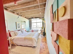 Ein Schlafzimmer mit einem Bett, einem Fenster und einer Wand mit geometrischen Mustern.