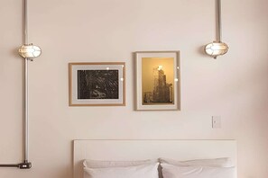 Ein Schlafzimmer mit einem Bett, zwei gerahmten Bildern an der Wand und zwei Pendelleuchten.