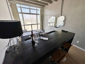 A modern room with a large window, a black table with a wine bottle and glasses, a lamp, and a mirror on the wall. - 2804B (São Paulo)