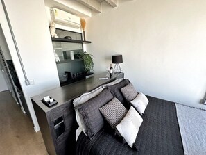 A modern bedroom with a large bed, a bedside table, a built-in shelf, and a small desk area. - 2804B (São Paulo)