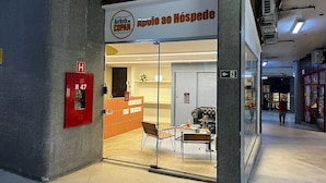 En hotelindgang med reception, brandalarm og en glasdør til indgangen.