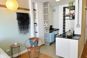 A compact kitchen with a central island, a dining area with a chair, and a hanging decorative element. - 2813B (São Paulo)
