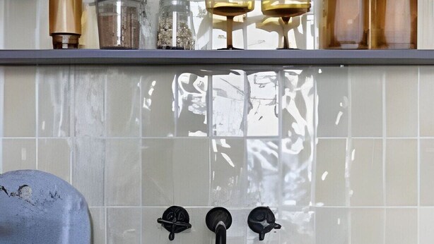A kitchen with a tiled backsplash, a sink with two faucets, and shelves with various kitchen items. - 3101B (São Paulo)