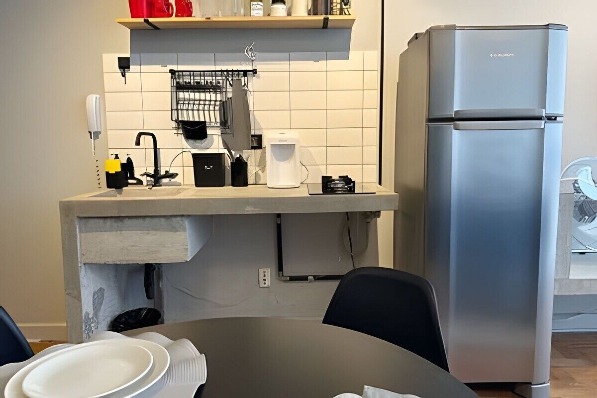 A compact kitchen with a built-in refrigerator, a coffee maker, and a sink with a faucet.