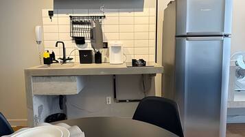 A compact kitchen with a built-in refrigerator, a coffee maker, and a sink with a faucet.