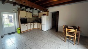 Une cuisine avec des meubles blancs, un réfrigérateur et une table à manger avec des chaises.