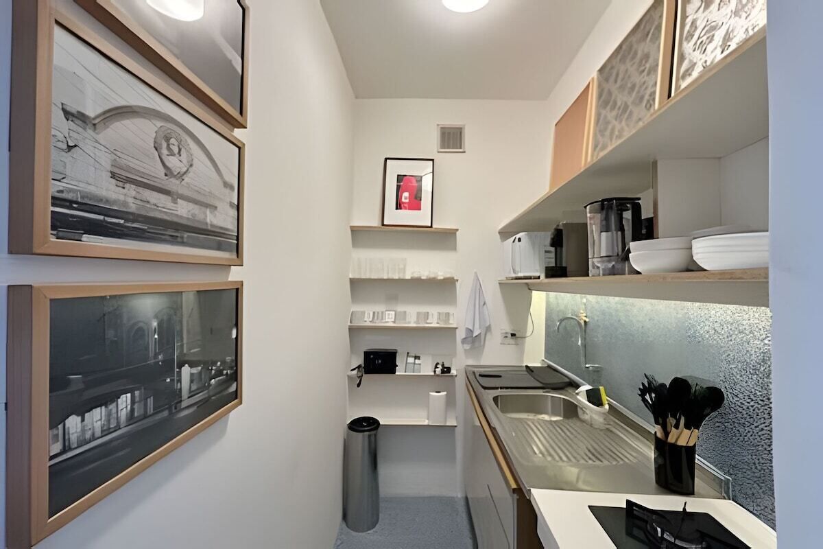Cocina compacta con lavabo, estufa y estanterías para guardar objetos.