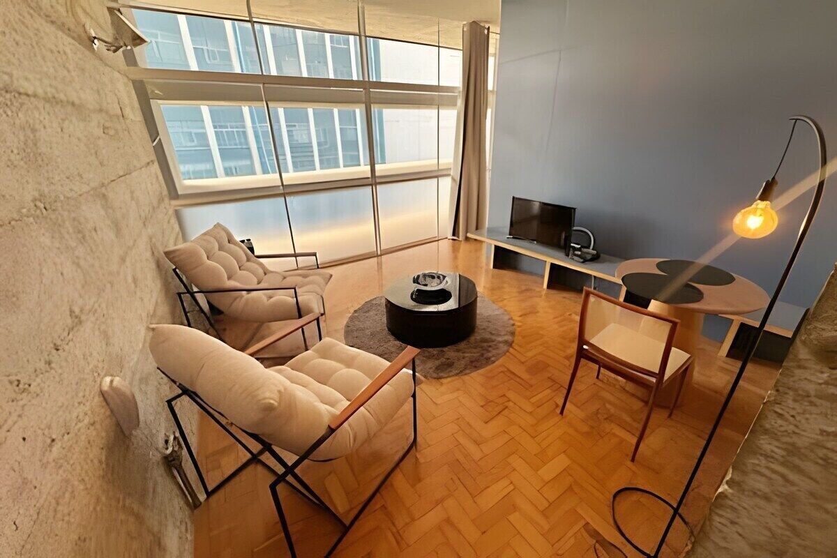A modern living room with a large window, a round coffee table, and a TV stand.