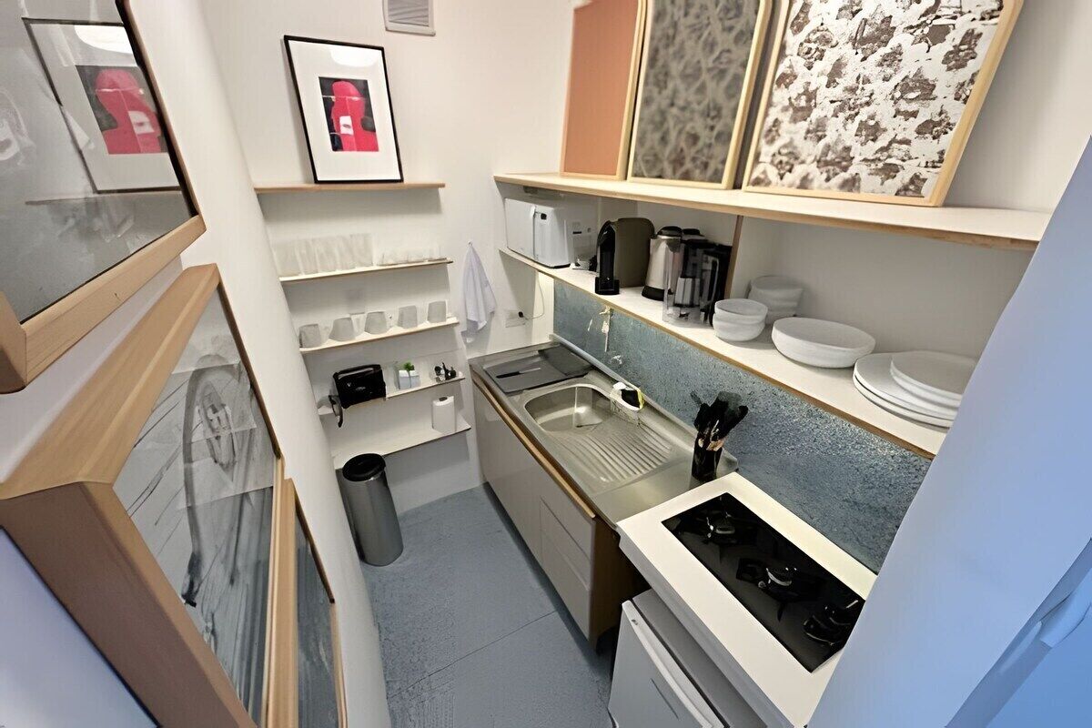Una cocina compacta con un lavamanos, estufa y estantes con utensilios de cocina.