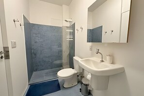 Ein Badezimmer mit Dusche, Toilette, Waschbecken und Spiegel.