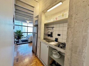 A compact kitchen with a built-in refrigerator, a gas stove, and a small sink. - 1207B (São Paulo)