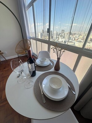 A dining area with a table set for two, a bottle of wine, and a vase with dried flowers. - 2606B (São Paulo)