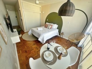 Une chambre à coucher comprenant un lit, une table de chevet et un coin repas avec des chaises et une table dressée pour deux personnes.