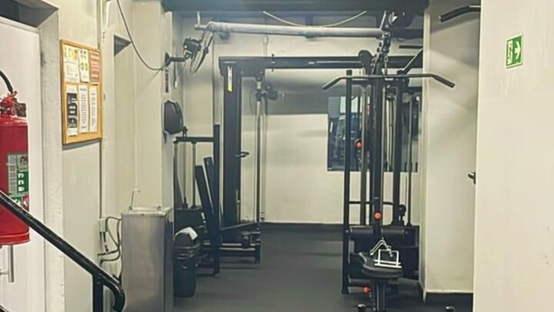 A gym with exercise equipment, a fire extinguisher, and a staircase. - 2606B (São Paulo)