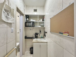 A compact kitchen with a microwave, coffee maker, and a small sink.