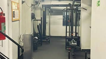 A gym with exercise equipment, a fire extinguisher, and a stairway.