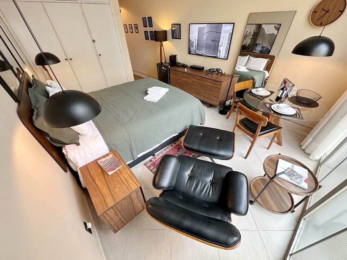 Ein modernes Hotelzimmer mit Bett, Schreibtisch, Stuhl, kleinem Tisch und Fernseher.