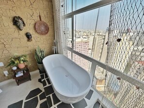 A bathroom with a freestanding bathtub, a potted plant, and a decorative wall piece. - 2610B (São Paulo)