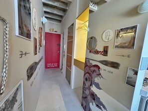 A hallway with artwork, a red door, and a wall-mounted mirror. - 2610B (São Paulo)