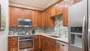 Una cucina moderna con mobili in legno, elettrodomestici in acciaio inossidabile, zoccolo a mosaico e lavastoviglie integrata.