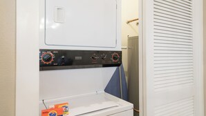 Lavanderia funzionale con lavatrice e asciugatrice a carica frontale, un pannello di controllo con diverse manopole e una scatola di detersivo Tide sull'asciugatrice.