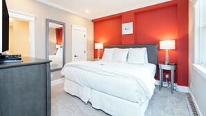 Una camera da letto moderna con un letto grande, due lampade ai comodini, una cassettiera e uno specchio.