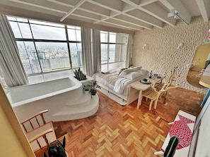 A modern living room with a large window, a curved seating area, and a dining space. - 2315B (São Paulo)