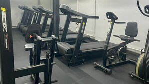 Une salle de sport équipée de tapis de course, de vélos elliptiques et de matériel de musculation.