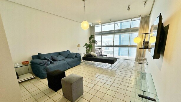 A modern living room with a sofa, ottoman, and glass coffee table. - 0121C (São Paulo)