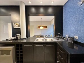 A modern kitchen with a built-in sink, dark cabinetry, and a blue tiled backsplash. - 0121C (São Paulo)
