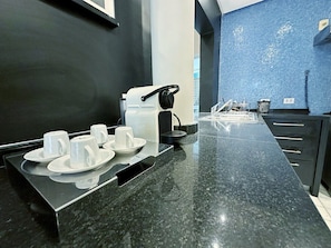 Eine Hotelküche mit Marmorarbeitsplatte, Kaffeemaschine und Wasserkocher.