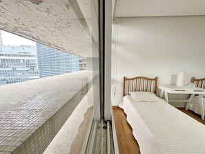 A hotel room with a balcony, a bed, a bedside table, and a window. - 0121C (São Paulo)