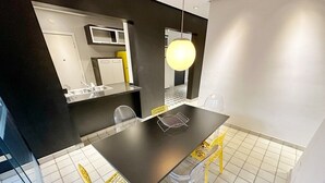 A modern dining area with a black table, yellow chairs, and a hanging light fixture. - 0121C (São Paulo)