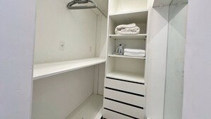 Un vestidor amplio con estantes y cajones, una barra para colgar y una toalla en el estante superior.