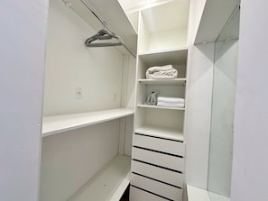 A white walk-in closet with shelves and drawers, a hanging rod, and a towel on the top shelf. - 1704B (São Paulo)