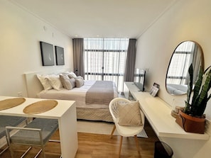 A modern bedroom with a bed, bedside table, chair, desk, and a large mirror. - 1704B (São Paulo)