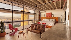 A modern hotel room with a large window, a bed, a leather sofa, and a small table. - 3220B (São Paulo)