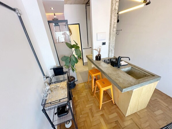 Una cocina moderna con suelo de madera en espiga, una barra con taburetes y una planta grande en maceta.
