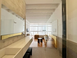 A modern hotel room with a large window, a bed, a small table, and a seating area. - 0713B (São Paulo)