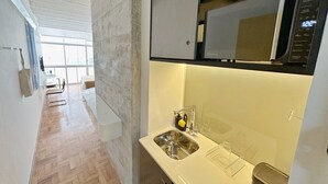 A modern kitchen with a stainless steel sink, a microwave, and a window providing natural light. - 0713B (São Paulo)