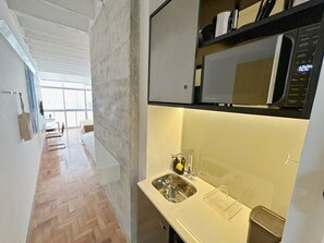 A modern kitchen with a stainless steel sink, a microwave, and a window providing natural light. - 0713B (São Paulo)