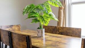 Une table à manger avec un pot de plante placé au centre, entourée de chaises en bois.