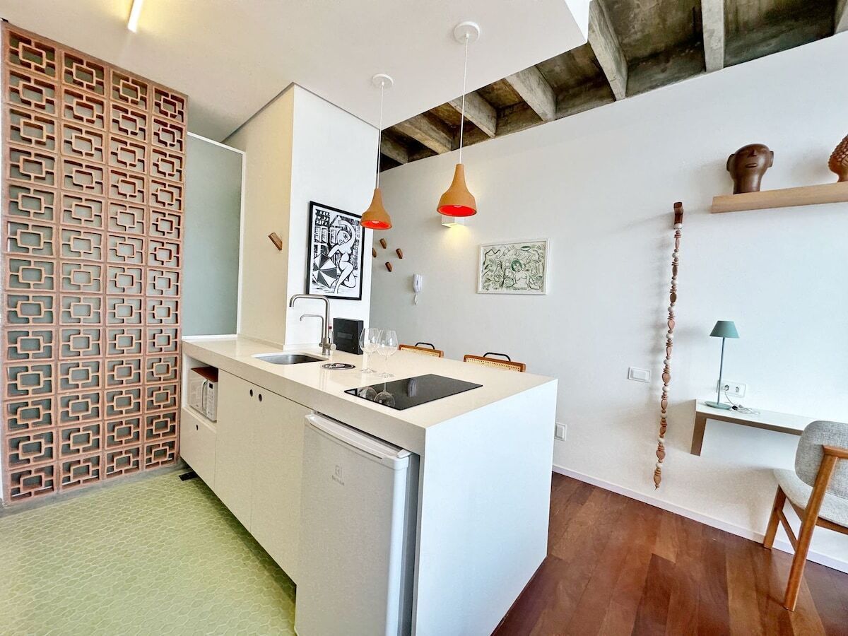 Eine moderne Küche mit einer weißen Kücheninsel, Pendelleuchten und Holzboden.