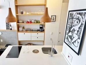 A modern kitchen with a white countertop, two pendant lights, a sink, and a framed artwork on the wall. - 3009B (São Paulo)