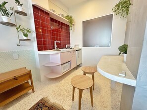 A compact kitchen with a microwave, a sink, and a small dining area with stools. - 2807B (São Paulo)