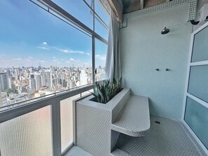 Ein Balkon mit Blick auf eine Stadtlandschaft, einem Blumentopf und einem Eckwaschbecken.