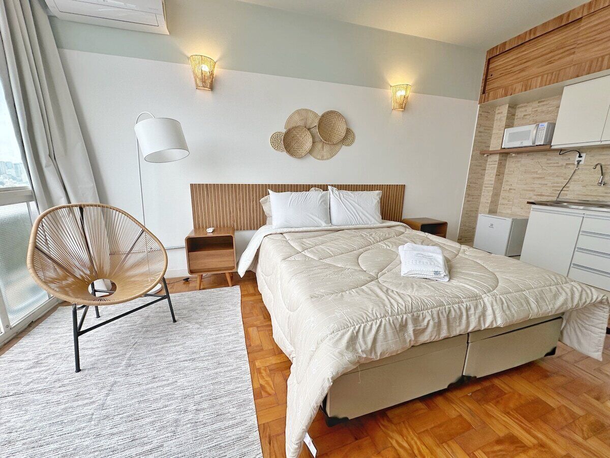 Une chambre à coucher moderne avec un lit, des tables de chevet, une chaise et un luminaire fixé au mur.