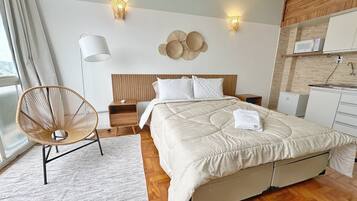 Une chambre à coucher moderne avec un lit, des tables de chevet, une chaise et un luminaire fixé au mur.